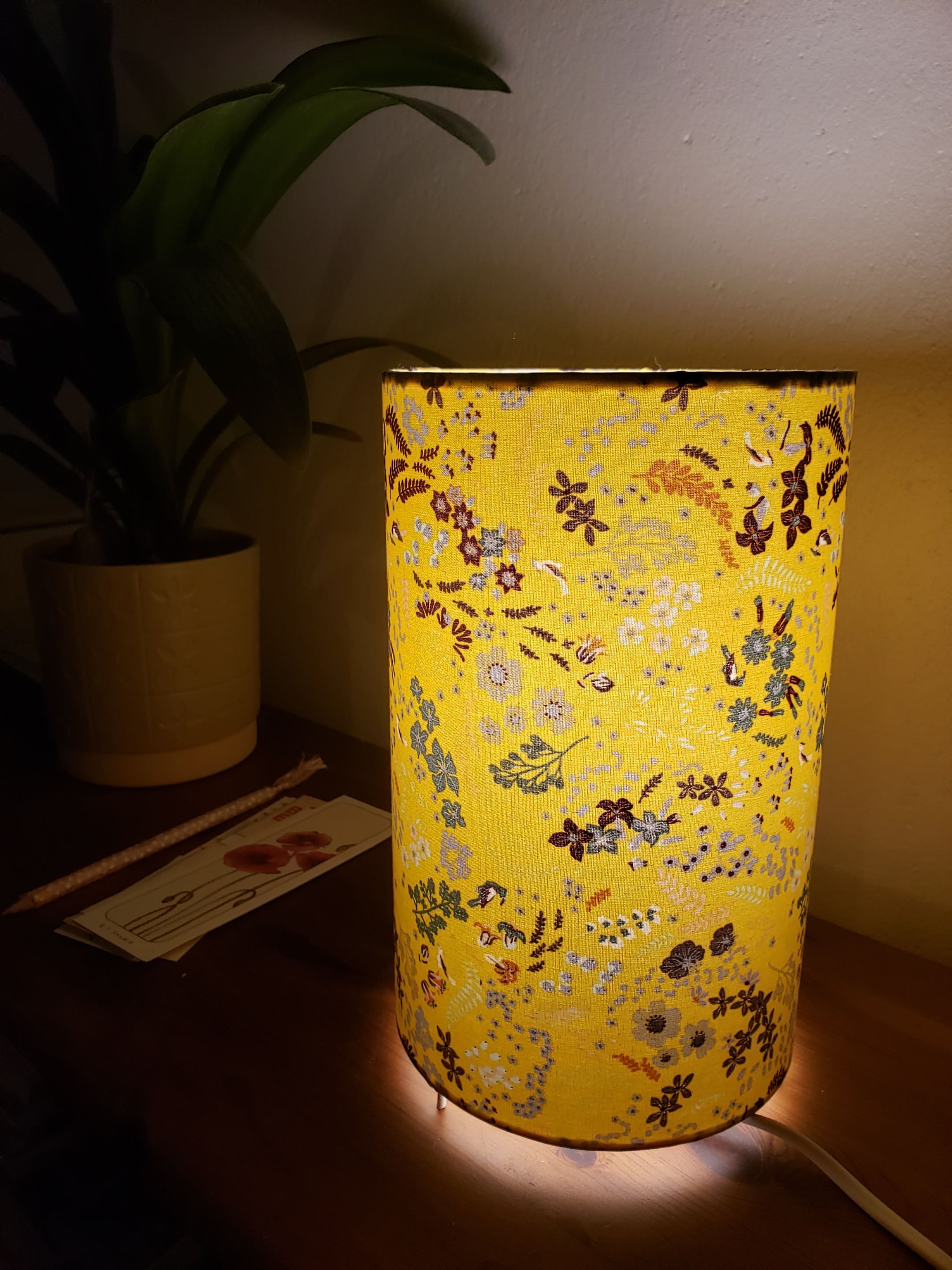 Photo d'une lampe en tissu cylindrique jaune avec de petits motifs végétaux